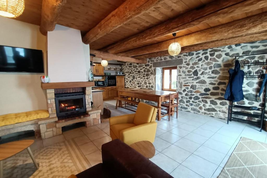 a living room with a stone fireplace and a table at Gite tout confort 10 pers à 8 km du Lioran in Saint-Jacques-des-Blats