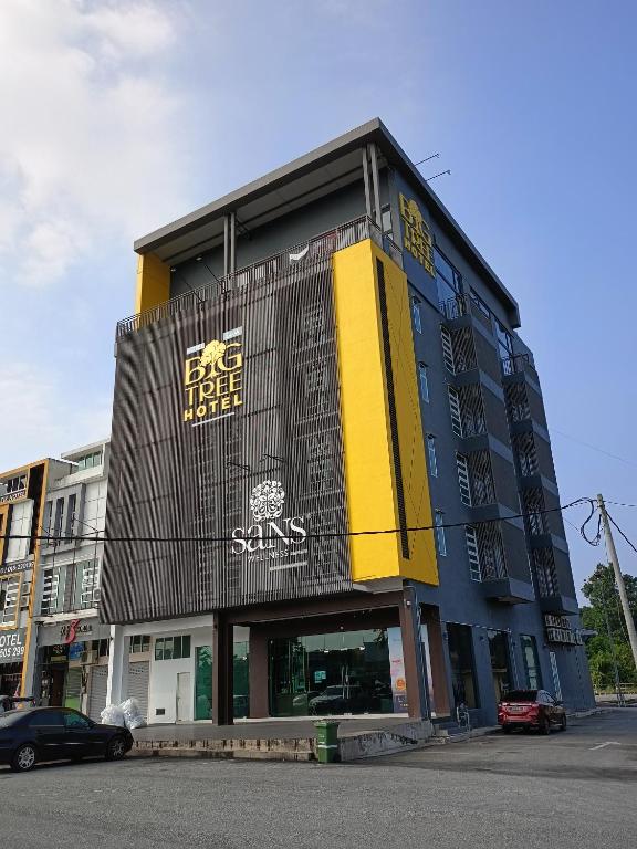 淡马鲁BIG TREE HOTEL的街道上的建筑,前面有汽车停放