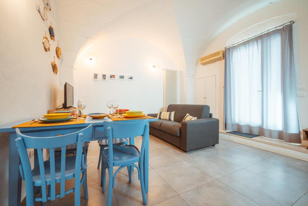 sala de estar con mesa azul y sillas en Poseidonia-Housea Travel, en Polignano a Mare