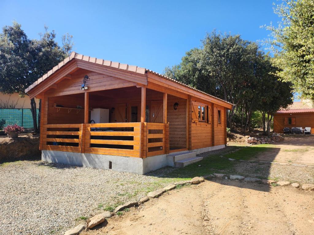 a small wooden cabin with a porch on a dirt road at Chalet 4 personnes à 5 mn des plages in Calcatoggio