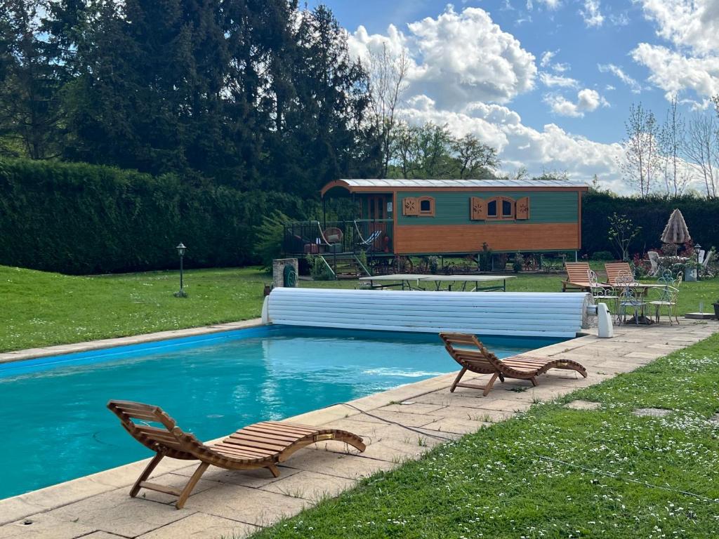 een zwembad met twee stoelen en een huis bij La Roulotte deluxe de Malpas in Quingey