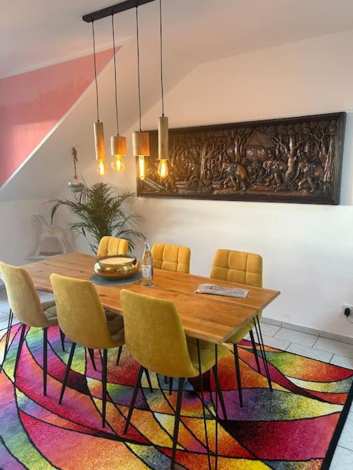 Crazy Home في هوكلهوفن: غرفة طعام مع طاولة وكراسي على سجادة ملونة