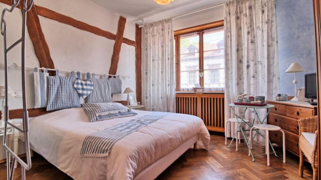 a bedroom with a bed and a desk and a window at Appartements & Chambres Les Loges du Capucin in Kaysersberg