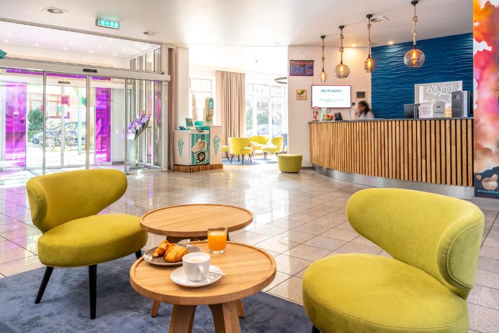 a lobby with two chairs and a table with a plate of food at ibis Styles Hamburg Alster City in Hamburg