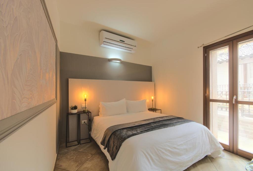 - une chambre avec un lit doté de draps blancs et une fenêtre dans l'établissement Imola Suites - Self Check-in, à Imola