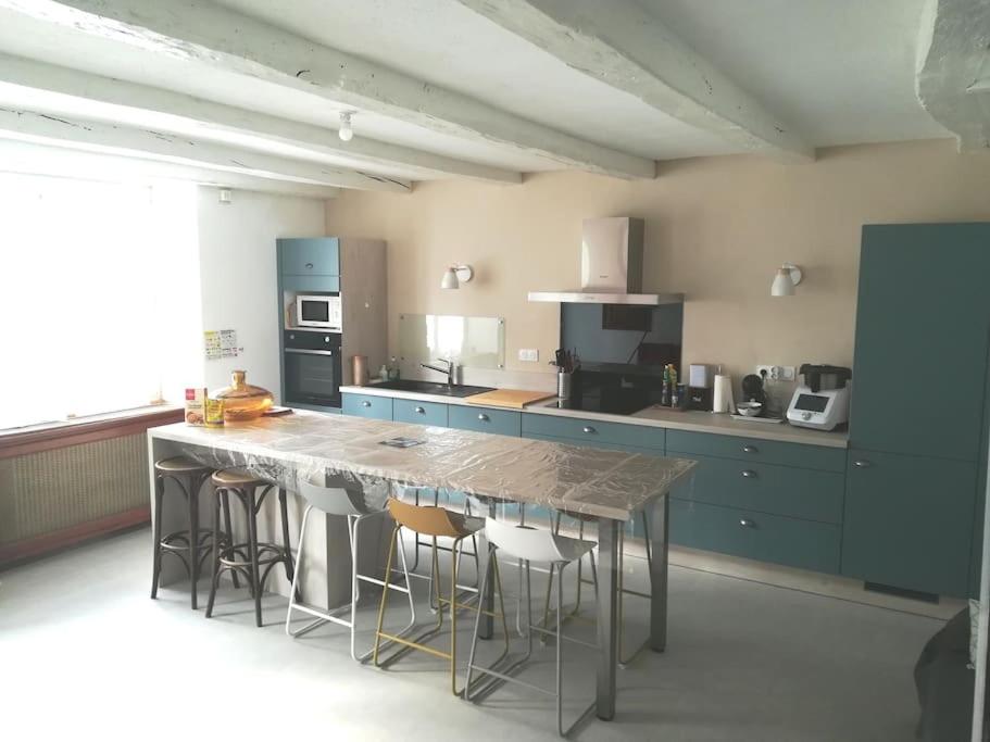 - une cuisine avec une grande table en bois et des tabourets dans l'établissement Maison dans la baie du Mont St Michel, à Genêts