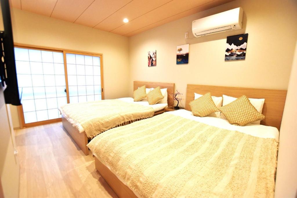 Un dormitorio con dos camas y una ventana. en Tamatsukan 玉津館, Detached Hse, JR Tsuruhashi 7min, Kansai Airport 關西空港 57 mins, Namba 6 mins, Nihonbashi 4 mins, Universal Studio 37 mins, Nara 30 mins, Early Check In, en Osaka