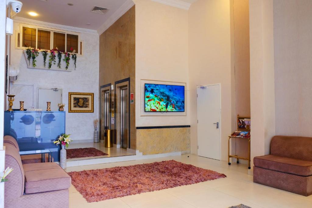 Liberty Avenue Hotel في الدوحة: غرفة معيشة مع أريكة وتلفزيون على الحائط