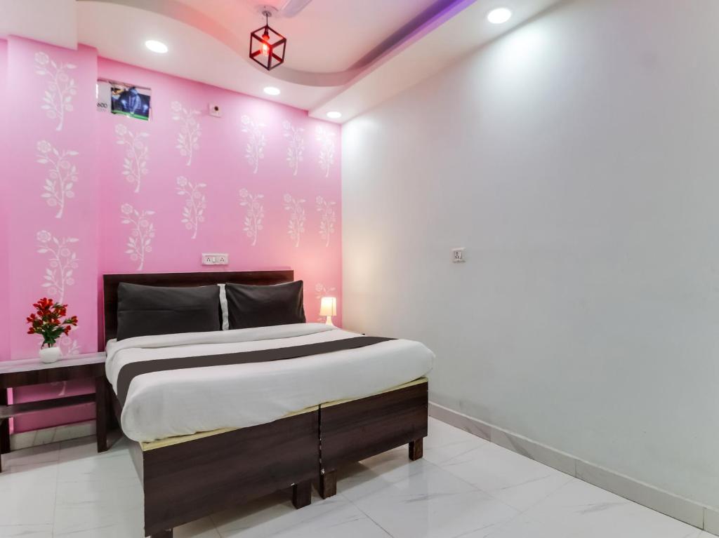 a bedroom with a pink wall with a bed at OYO Silent Moon Hotel in New Delhi