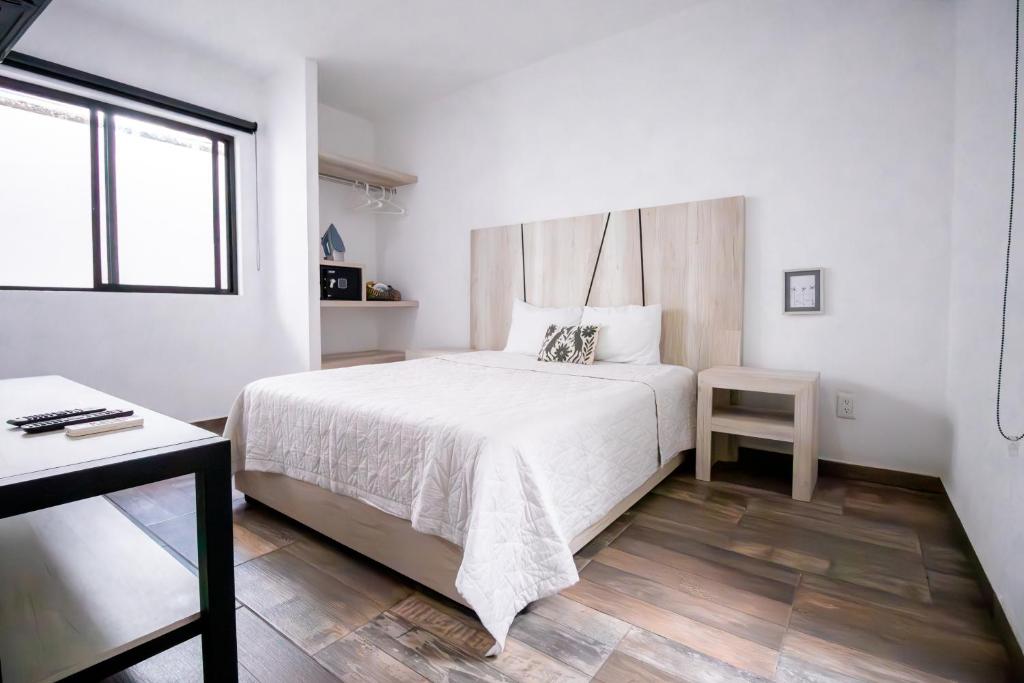 Dormitorio blanco con cama y mesa en Arkana 9 Suites Grupo Amber - Collection O en Playa del Carmen
