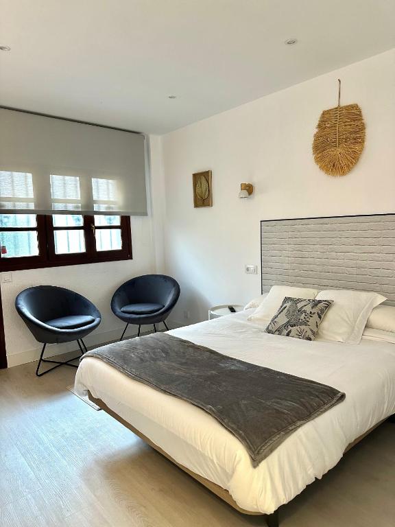 sypialnia z dużym łóżkiem i 2 krzesłami w obiekcie Apartamentos Val de Comillas w mieście Comillas
