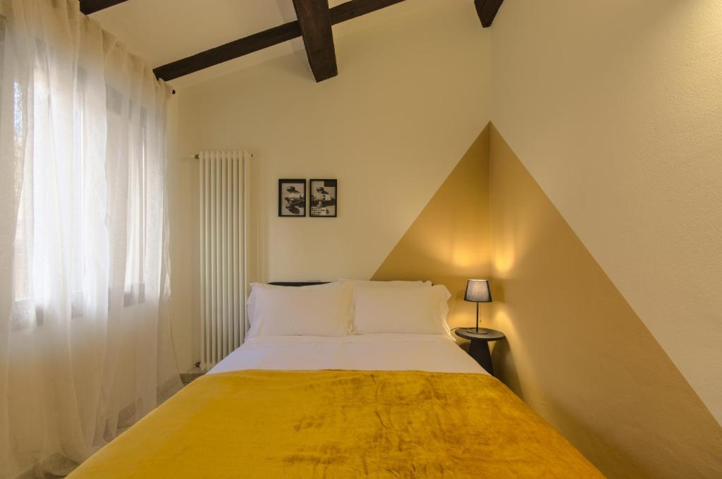 - une chambre avec un grand lit et une couverture jaune dans l'établissement Imola Residence - Self Check-in, à Imola