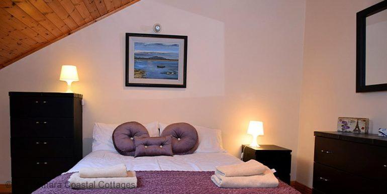 a bedroom with a bed with a brown chair at Cleggan 318 Atlantic Lodge in Cleggan