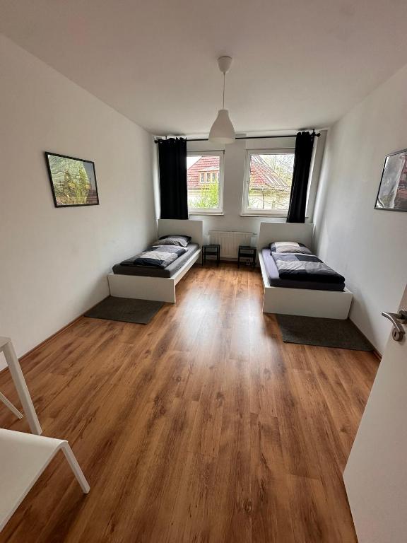 Cette chambre dispose de 2 lits, de parquet et de 2 fenêtres. dans l'établissement Domum 9 Moderne Ferien- Monteurapartments inkl Wlan und Waschmaschine, à Marl