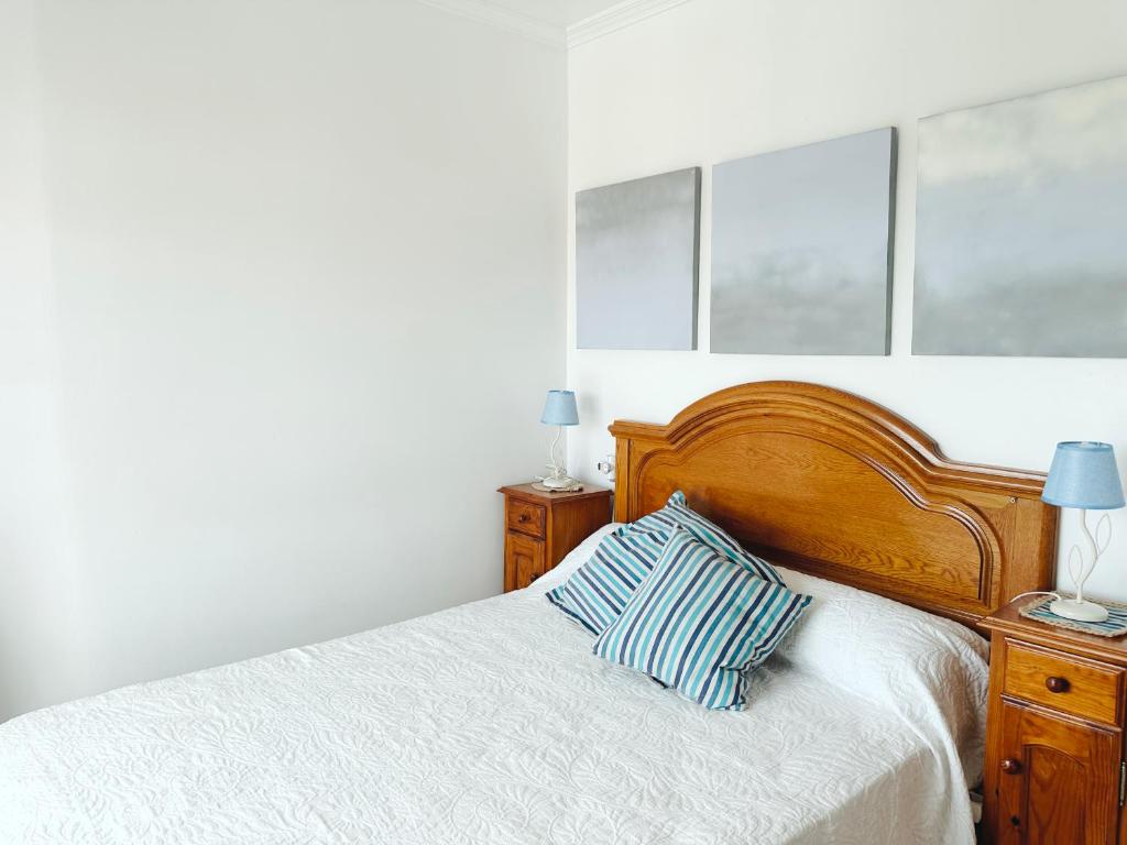 ein Bett mit einem hölzernen Kopfteil und einem Kissen darauf in der Unterkunft Casa Ana in O Grove