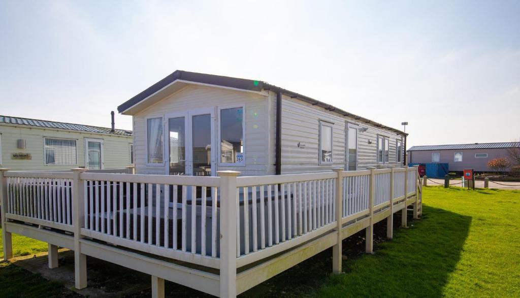 a mobile home with a white railing on the grass at WW265 Camber Sands Holiday Park in Camber