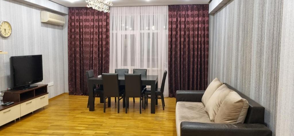 a dining room with a table and chairs and a television at Boulevard view spacious apartment in Baku in Baku