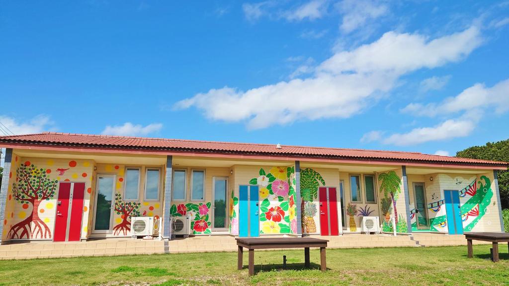 ein Gebäude mit bunten Türen und Fenstern mit zwei Picknicktischen in der Unterkunft Alezed Villa Shiraho in Ishigaki-jima
