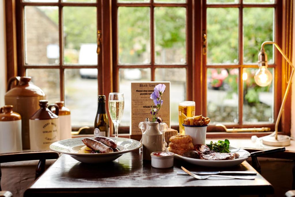 une table avec deux assiettes de nourriture et une fenêtre dans l'établissement Black Lion Inn, à Leek