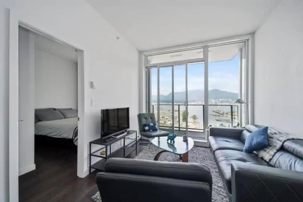 salon z kanapą, telewizorem i łóżkiem w obiekcie Bright and Modern Suite with Amazing views! w mieście Vancouver