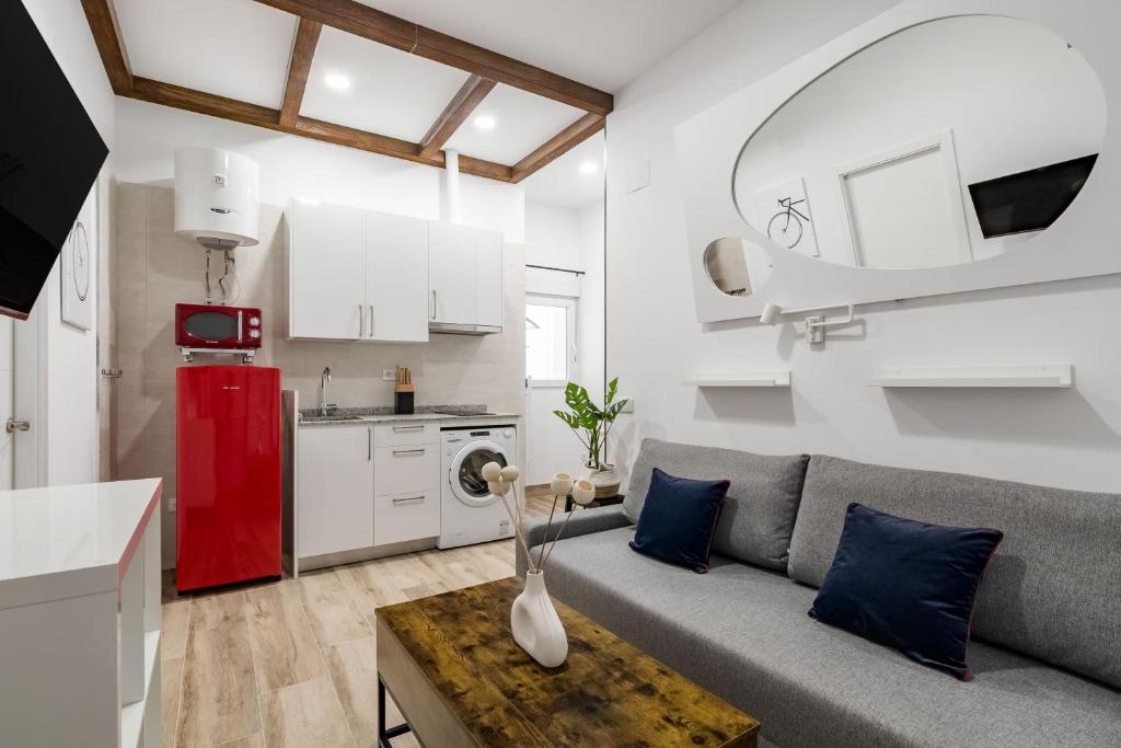 Una sala de estar con un sofá y un refrigerador rojo. en Madrid Villaverde - Apartamentos acogedores, AC, en Madrid