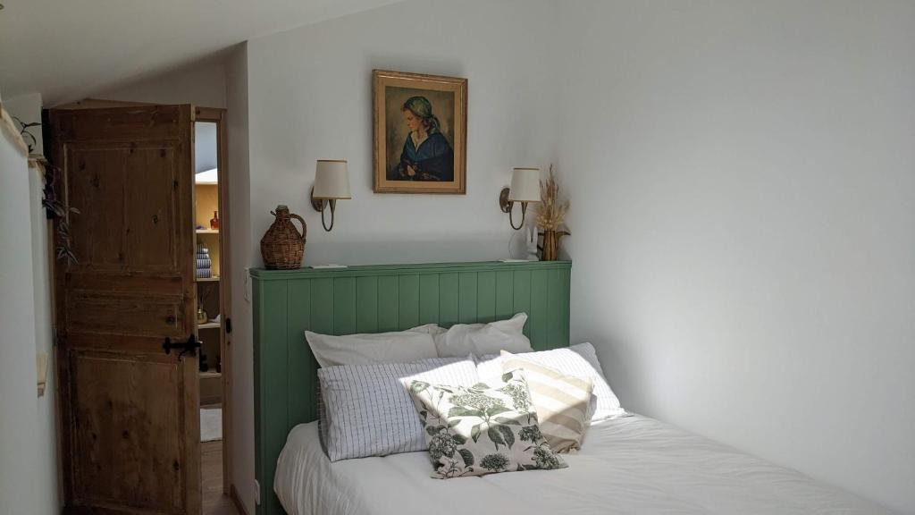 1 dormitorio con 1 cama con cabecero verde y almohadas en La Bonne du Curé, en Annoville