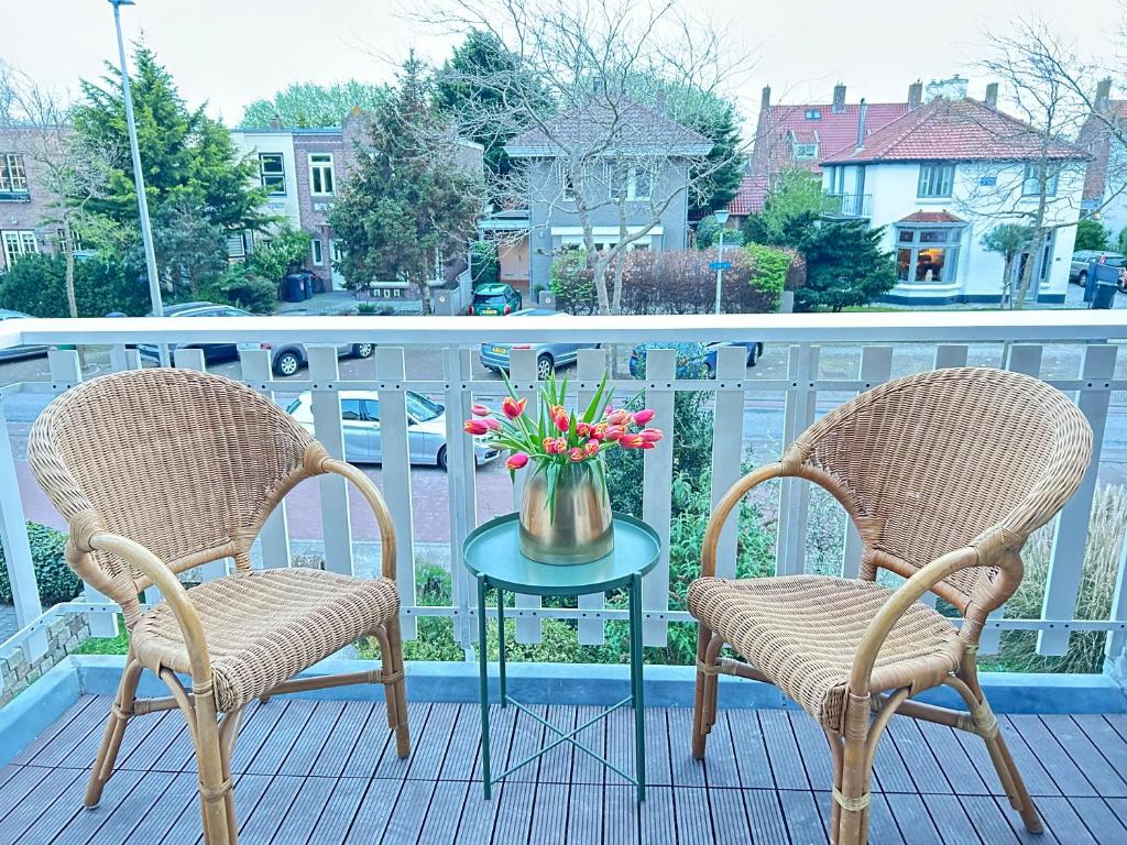 two chairs and a table with flowers on a balcony at Lovely Spacious Apartment in Zandvoort