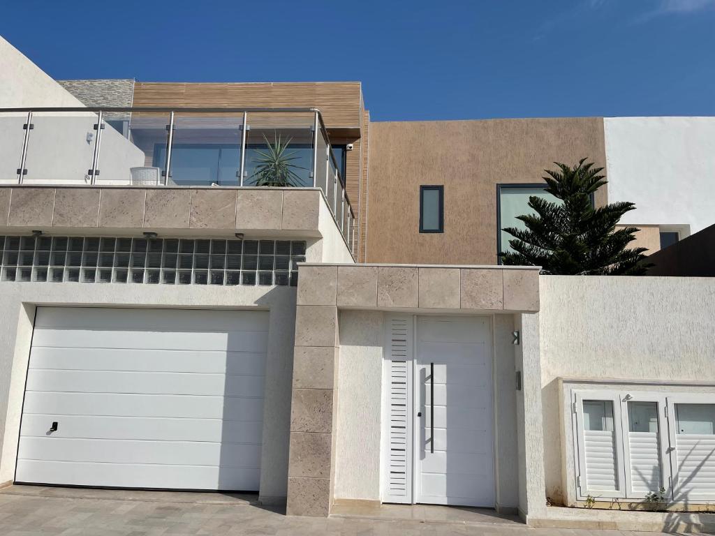 Casa con puertas blancas de garaje y balcón en Luxury house with swimming pool, en Ben Arous