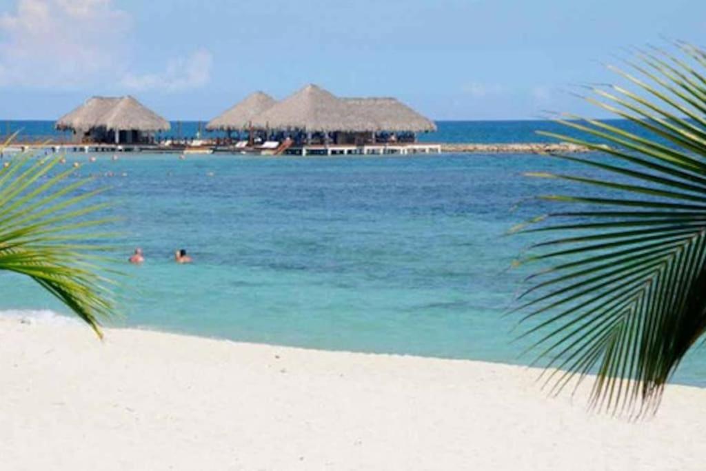 una playa con sombrillas y gente en el agua en Appartamento Aruba Juan Dolio fronte mare, en Juan Dolio