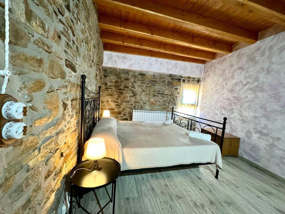 a bedroom with a bed in a stone wall at La casa de Claverol in Claverol