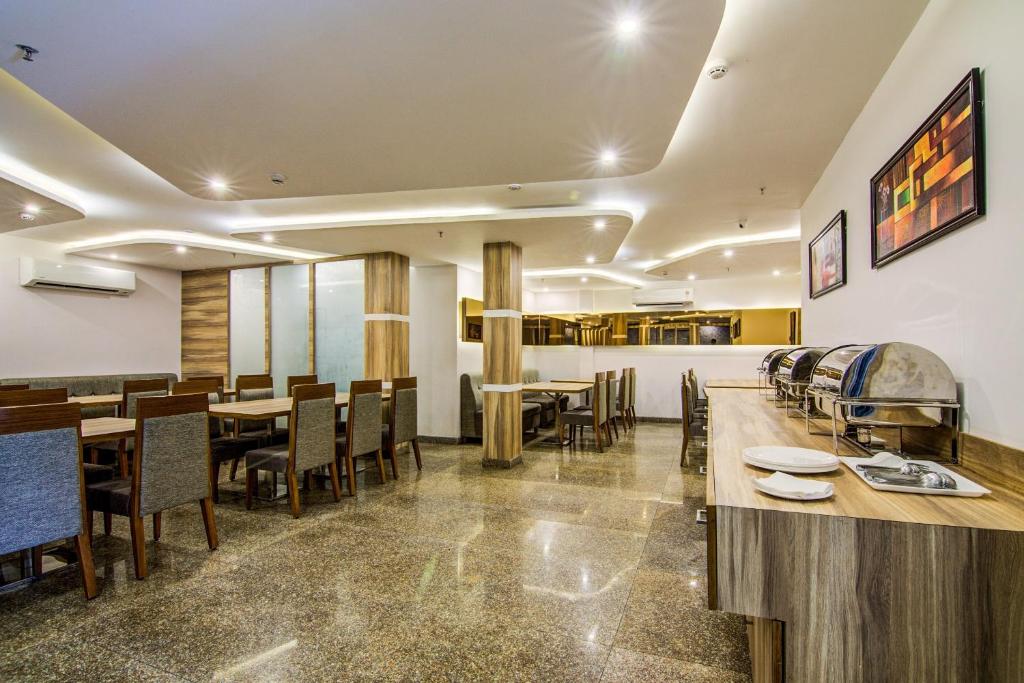 a restaurant with tables and chairs in a room at Pratibha Grand in Vijayawāda