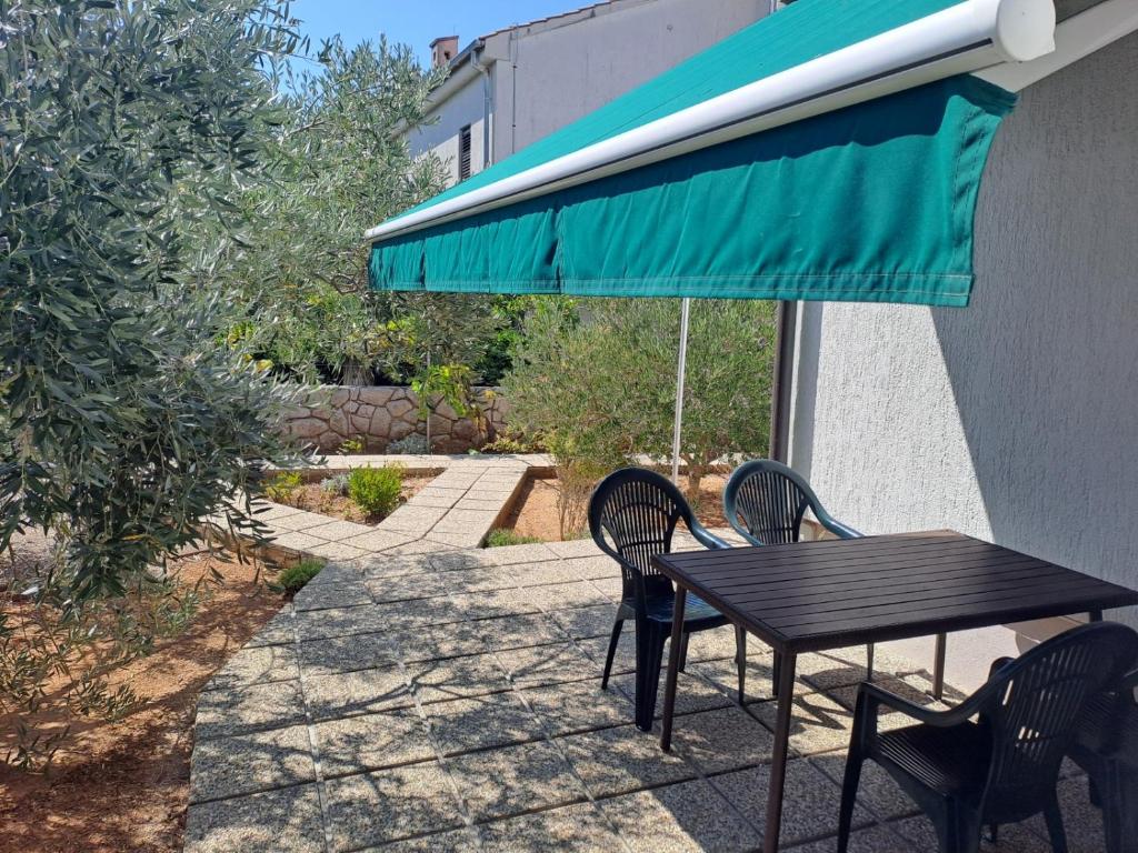 a table with two chairs and a green umbrella at Apartment in Punat with Terrace, Air conditioning, Wi-Fi, Washing machine (3829-2) in Punat