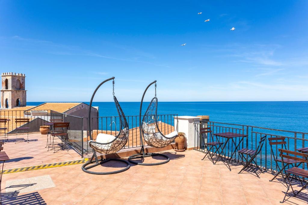 een terras met stoelen en uitzicht op de oceaan bij Dolce Vita Rooms and Apartments in Cefalù