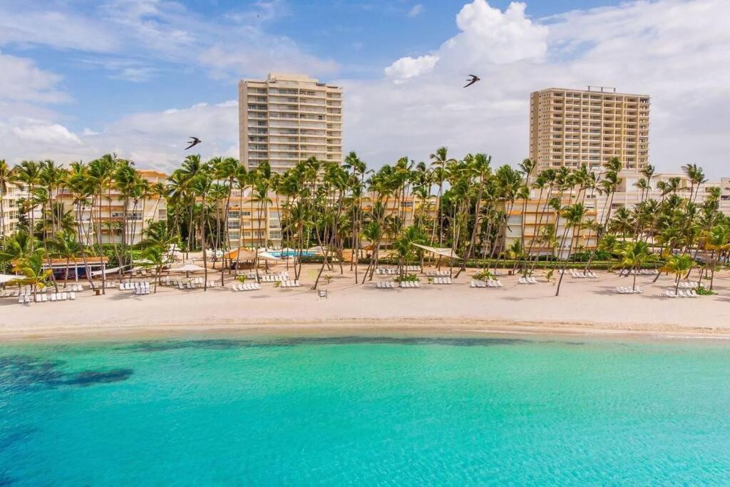 una playa con sillas, palmeras y edificios en Appartamento Bequia Juan Dolio fronte mare, en Juan Pedro
