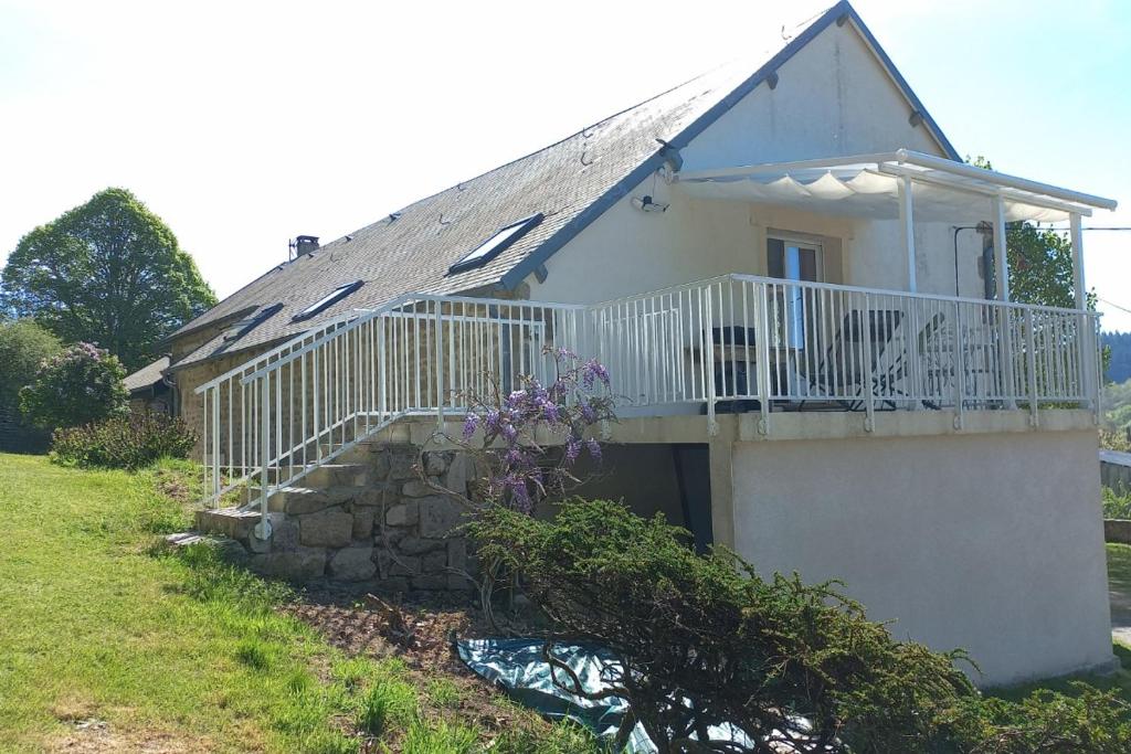 Casa blanca con balcón y pared de piedra en Gîte Le Chardet 
