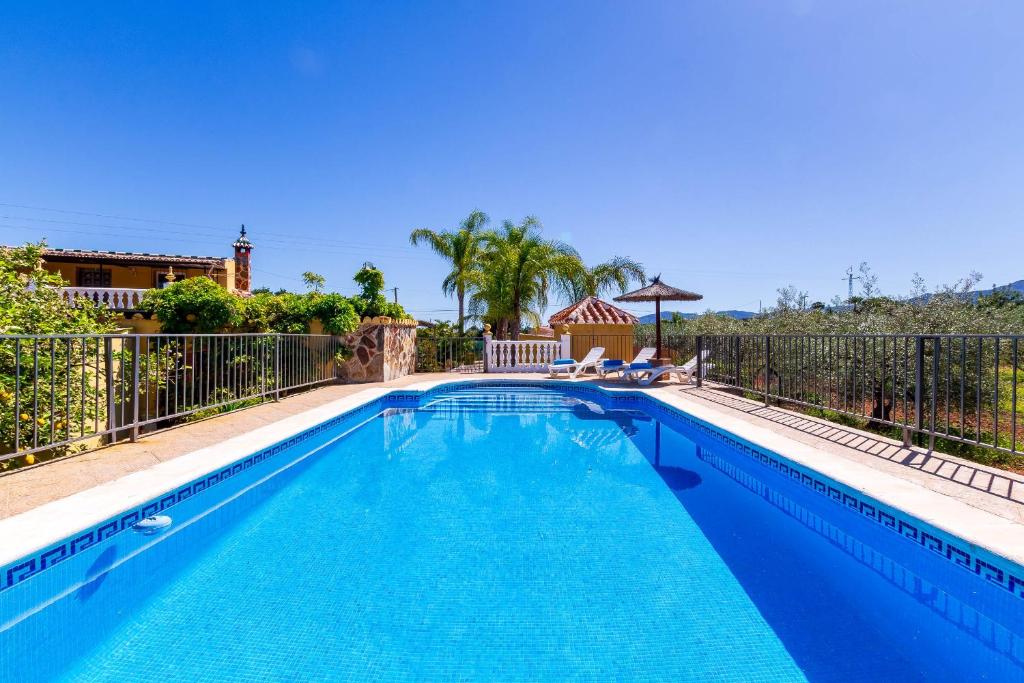 a swimming pool with a fence and a blue pool at Casa Rural La Colina a 30 min Málaga Lovely Home in Alhaurín de la Torre