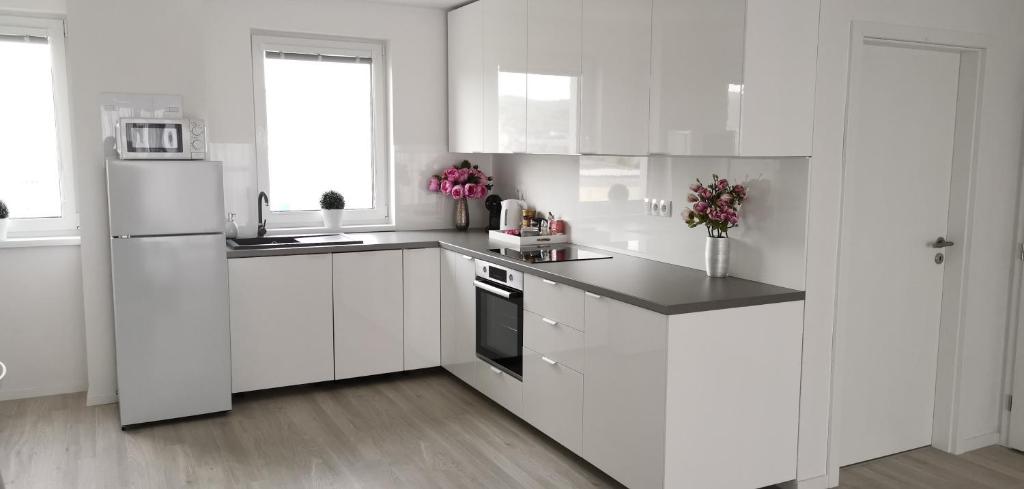 a white kitchen with white cabinets and a refrigerator at Rendez - 2 spálňový 85m2 veľký byt v novostavbe s parkovacím miestom in Rača