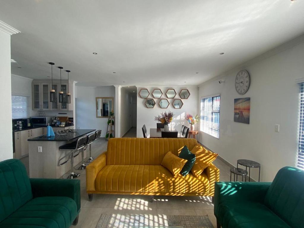a living room with a yellow couch and a kitchen at 32 On Gill Road Self Catering in Cape Town