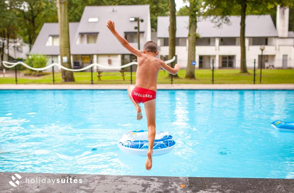 un joven saltando a una piscina en Holiday Suites Limburg, en Aan de Wolfsberg