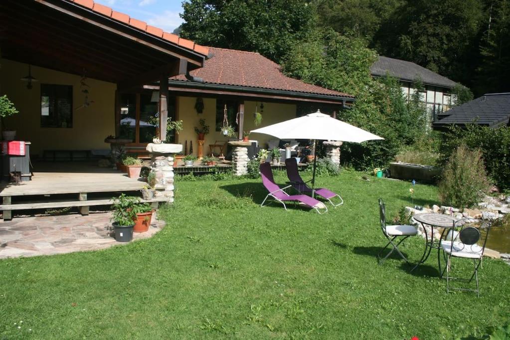 einen Garten mit Stühlen, einem Tisch und einem Sonnenschirm in der Unterkunft Le Loft House Jaun in Im Fang