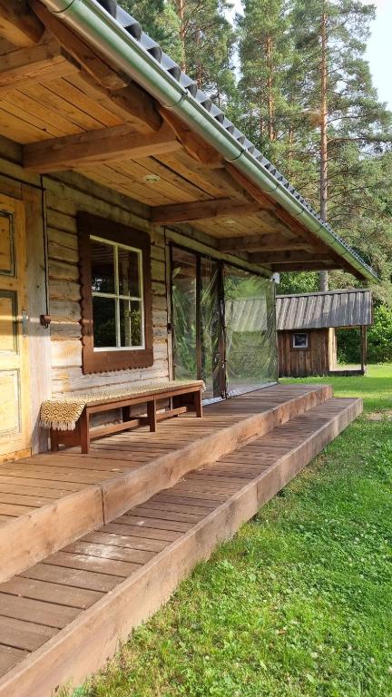 un porche de madera de una cabaña con banco en Oandu Camping, en Oandu