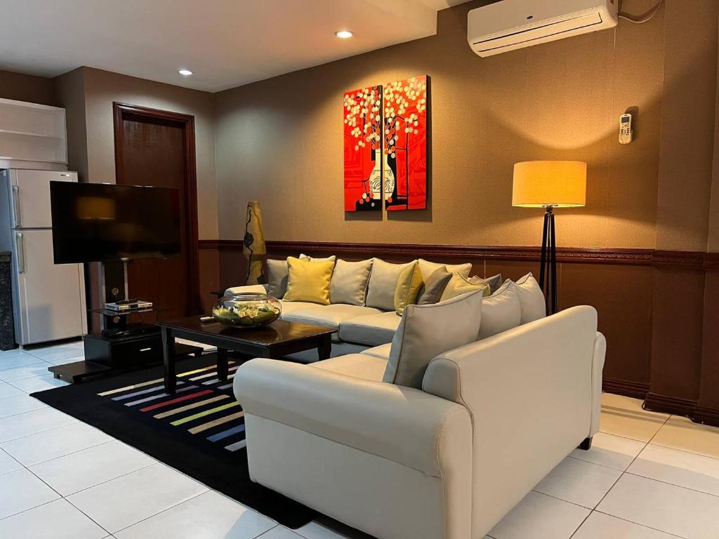 sala de estar con sofá blanco y TV en Subic Residencias, en Olóngapo