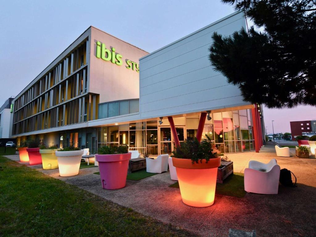un bâtiment avec des pots de plantes devant lui dans l'établissement ibis Styles Nantes Reze Aéroport, à Rezé