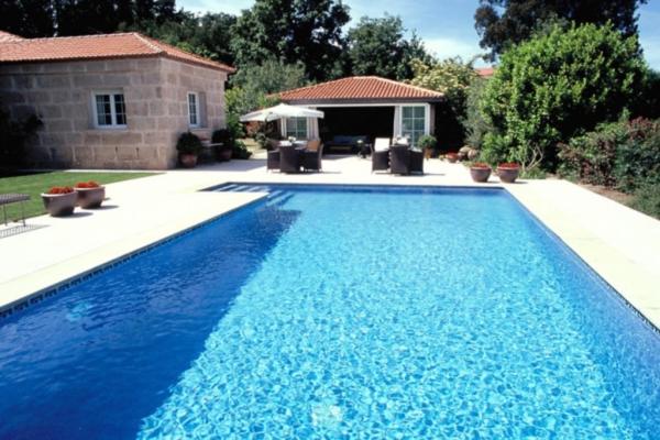 una gran piscina azul frente a una casa en Finca A Coutada., en Celanova