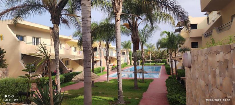 einen Innenhof des Resorts mit Palmen und einem Pool in der Unterkunft Appartement RESIDENCE « RAYANE BEACH » in Sidi Rahal