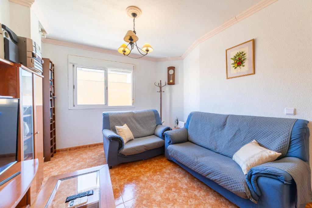 a living room with a blue couch and a tv at Edificio Merlin in Roquetas de Mar