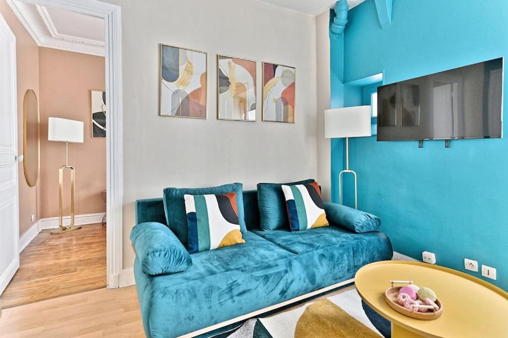 un salon avec un canapé bleu et une table dans l'établissement Appartement coloré Paris Rue Niépce, à Paris