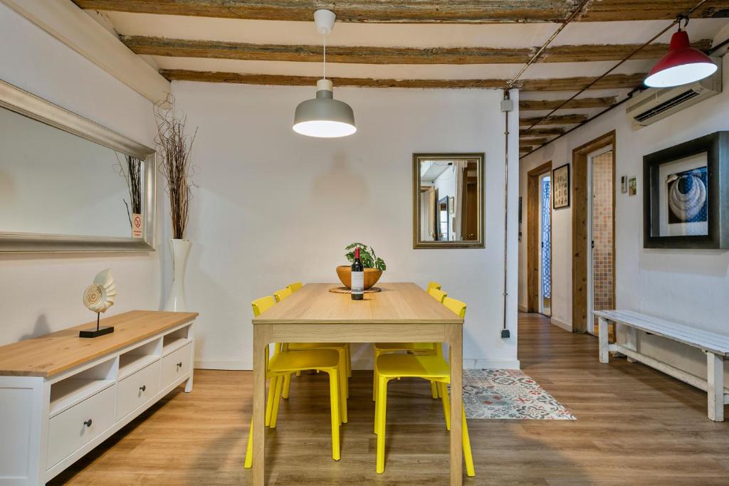 a dining room with a table and yellow chairs at Encanto en Las Ramblas: Espacio perfecto para 9 in Barcelona