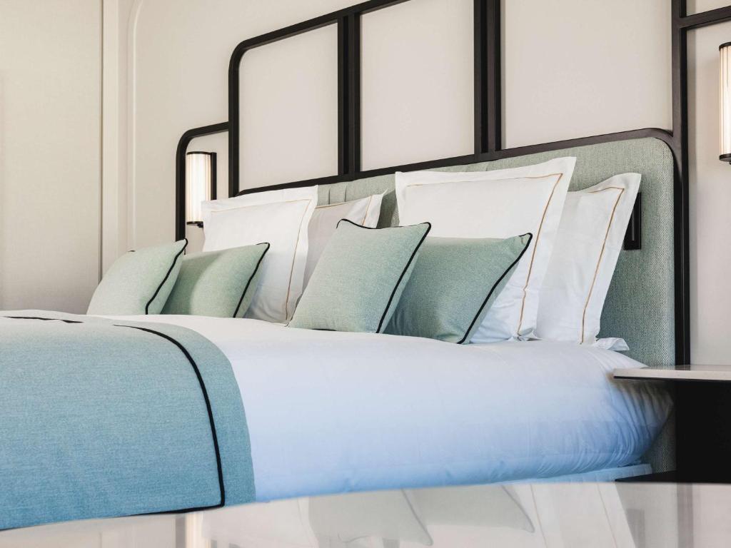 a bed with blue and white pillows on it at Mondrian Cannes in Cannes