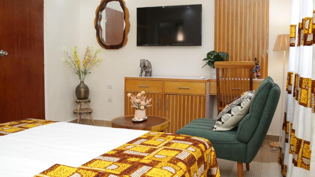 Habitación de hotel con cama, silla y TV. en Hotel Le Marly, en Abiyán